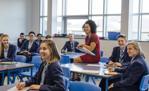 Teacher sitting on desk with students
